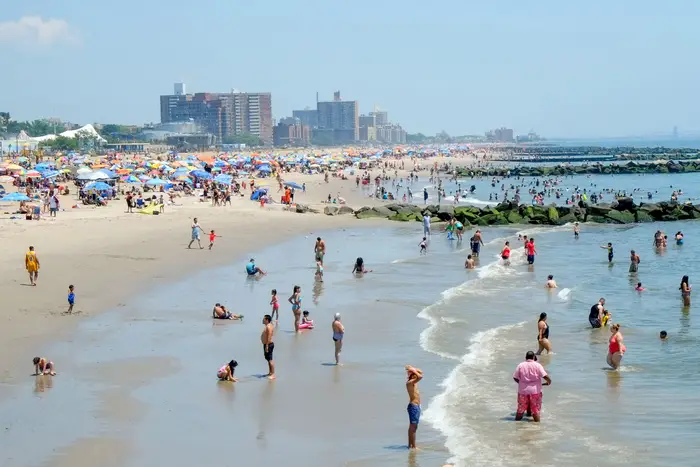 Hundreds of people are enjoy the beach and water at Coney Island